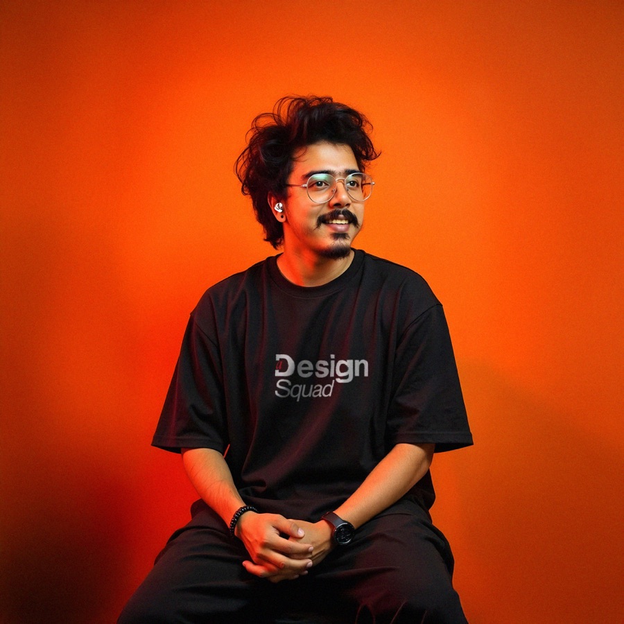 Sreerag C seated against an orange studio backdrop